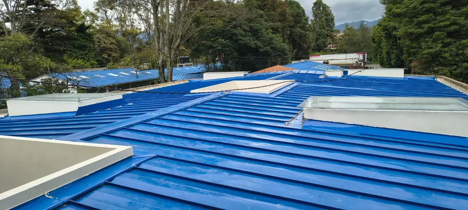 Cubierta azul con claraboyas de vidrio entre árboles