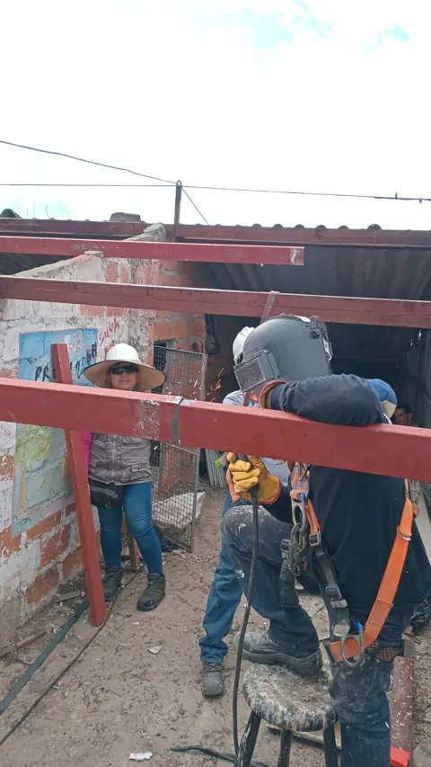 Equipo soldando la estructura metálica roja de una cubierta nueva