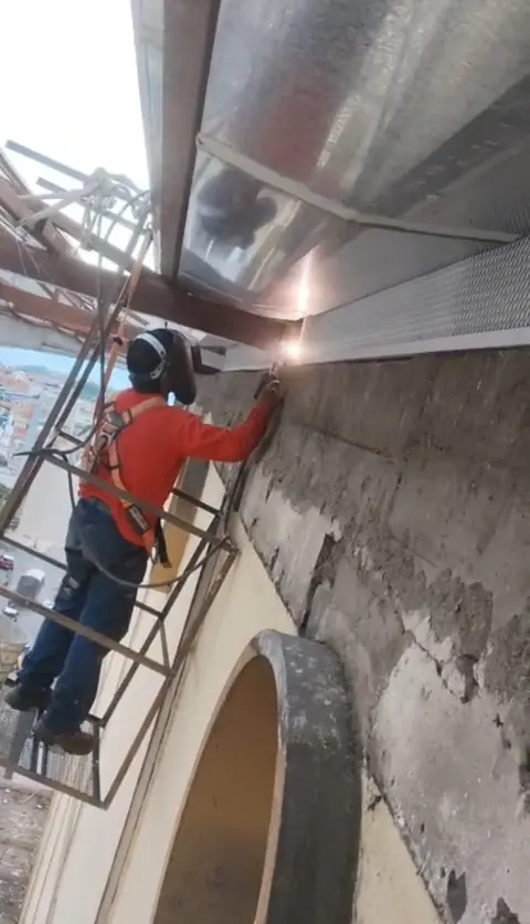 Soldador con arnés de seguridad en fachada